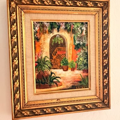 Sale Photo Thumbnail #39: Framed oil painting depicting a Mediterranean-style courtyard with potted plants, housed in an ornate gold-gilded frame with a linen liner.