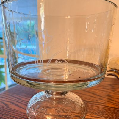 Sale Photo Thumbnail #95: Clear glass pedestal trifle bowl featuring frosted floral etchings on the exterior and a molded flower design on the domed base.