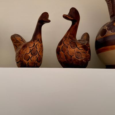 Sale Photo Thumbnail #32: Pair of vintage hand-carved wooden duck figurines with detailed feather patterns, displayed on a shelf.