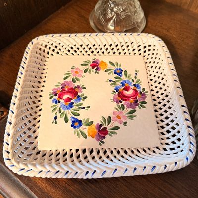 Sale Photo Thumbnail #116: Hand-painted square ceramic reticulated basket tray, featuring a central floral wreath motif with blue-trimmed woven lattice edges.