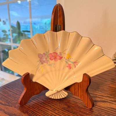Sale Photo Thumbnail #81: Vintage fan-shaped ceramic tray with delicate floral design and gold trim, displayed on a wooden stand.