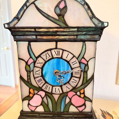 Sale Photo Thumbnail #4: Tiffany-style stained glass mantel clock featuring a floral iris motif, Roman numeral dial, and ornate metal hands.