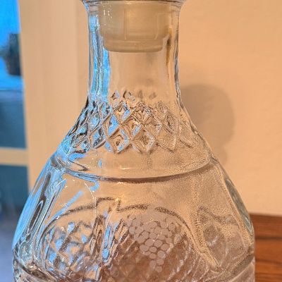Sale Photo Thumbnail #70: Vintage pressed crystal decanter featuring a diamond-cut pattern and etched grape cluster design with matching round glass stopper.