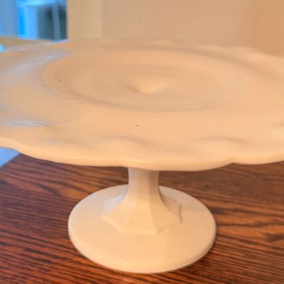 Sale Photo Thumbnail #96: Vintage white milk glass pedestal cake stand featuring a ruffled edge and molded stem.