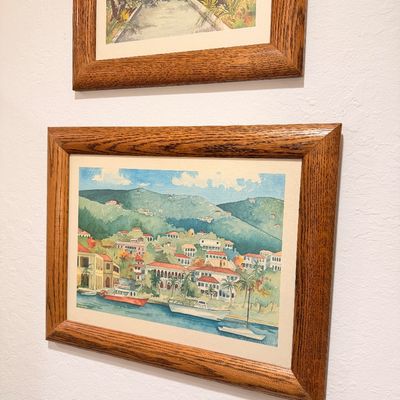 Sale Photo Thumbnail #51: Pair of framed watercolor prints depicting tropical coastal and architectural scenes, housed in matching oak wood frames.