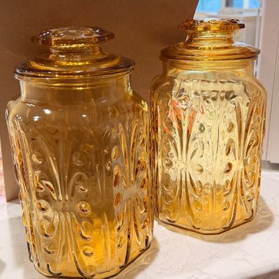 Sale Photo Thumbnail #57: Pair of vintage amber glass canister jars featuring an embossed scrolled pattern and matching lids.