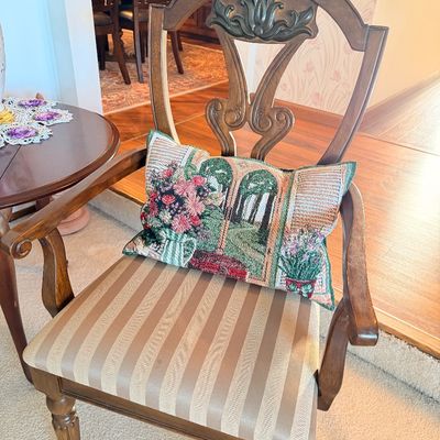 Sale Photo Thumbnail #3: Traditional wooden armchair featuring an ornate carved backrest, striped fabric upholstered seat, and a decorative tapestry throw pillow.