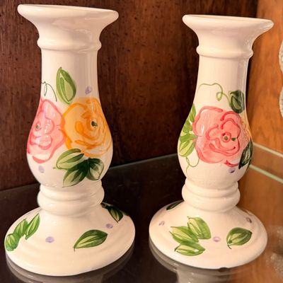 Sale Photo Thumbnail #112: Pair of hand-painted ceramic candlesticks featuring pink and yellow floral rose motifs with green foliage accents.