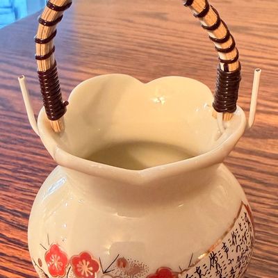 Sale Photo Thumbnail #86: Vintage Japanese ceramic teapot featuring hand-painted floral motifs and calligraphic text, finished with a bound bamboo overhead handle.
