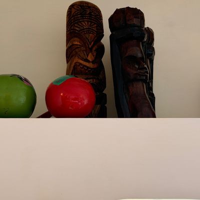 Sale Photo Thumbnail #30: Hand-carved wooden tiki statues and colorful painted maracas displayed on a shelf.