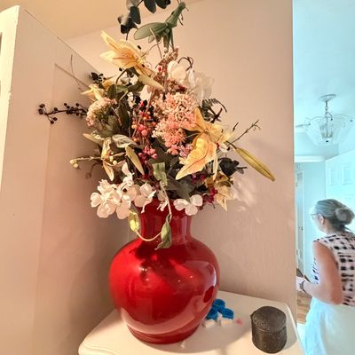 Sale Photo Thumbnail #49: Large glossy red ceramic vase filled with an assortment of faux flowers and foliage, displayed on a white wooden console table.