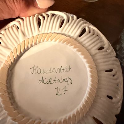 Sale Photo Thumbnail #115: Underside of a vintage ceramic reticulated plate featuring a hand-written mark that reads "Handarbeit dísztárgy KF".