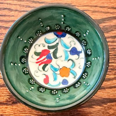 Sale Photo Thumbnail #104: Hand-painted Turkish Iznik-style ceramic bowl featuring a green glazed rim with dotted accents and a colorful floral center.