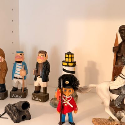 Sale Photo Thumbnail #43: Collection of vintage hand-painted figurines, including Swedish Visby wooden sailors, a British Royal Guard, a miniature lighthouse, and a mounted soldier.