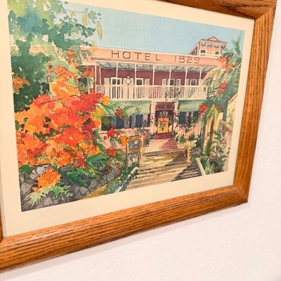 Sale Photo Thumbnail #52: Framed watercolor print depicting the historic Hotel 1829 in St. Thomas, housed in a simple oak wood frame.