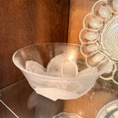 Sale Photo Thumbnail #118: Lalique-style frosted and clear glass bowl with a leaf motif, displayed alongside pressed glass serving pieces inside a wooden cabinet.