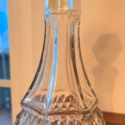 Sale Photo Thumbnail #72: Vintage pressed clear glass decanter featuring a diamond point pattern on the base and stopper with a panel-cut neck.
