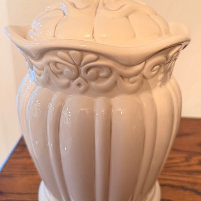 Sale Photo Thumbnail #61: Off-white ceramic glazed canister with matching lid, featuring raised scrollwork detail and vertical fluting.