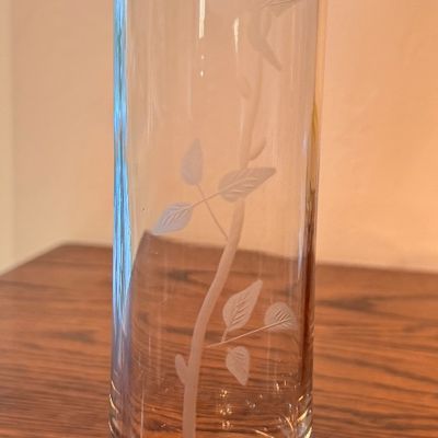 Sale Photo Thumbnail #108: Tall clear glass bud vase featuring a delicate etched long-stem rose motif and a heavy weighted base.
