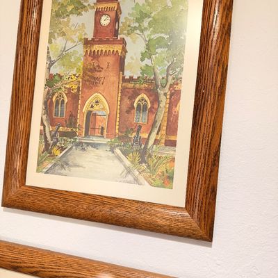 Sale Photo Thumbnail #54: Framed watercolor print depicting a historic brick fort with a clock tower and cannons, housed in a classic oak frame.