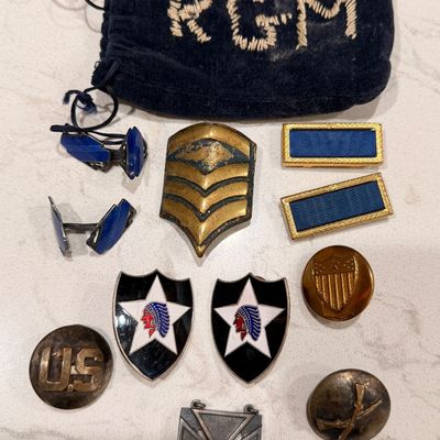 Sale Photo Thumbnail #56: Collection of vintage US military insignia, including 2nd Infantry Division enamel pins, rank chevrons, uniform buttons, cuff links, and a marksmanship medal, accompanied by a monogrammed drawstring pouch.