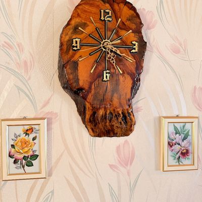 Sale Photo Thumbnail #5: Vintage live-edge wood slab wall clock with a high-gloss finish, flanked by two small framed floral prints.
