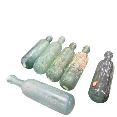 Sale Photo Thumbnail #46: Collection of six antique torpedo-style glass bottles, including embossed ginger ale and soda bottles with aged patina and wear.
