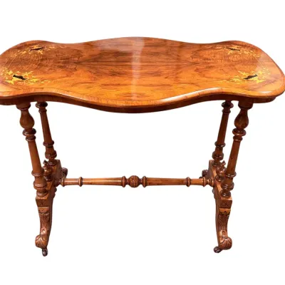 Sale Photo Thumbnail #2: Antique Italian burl walnut library table featuring a serpentine top with inlaid floral details, turned legs, and a carved stretcher base on casters.