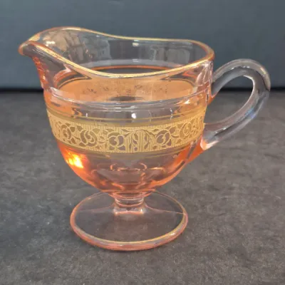 Depression-era pink glass creamer featuring a gold-encrusted floral band and gold-trimmed rim.