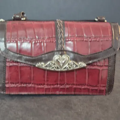 Brighton red faux-croc leather crossbody purse featuring brown trim and a silver-tone heart-shaped metal clasp.