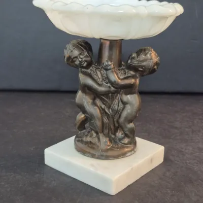 Vintage cherub compote dish featuring a bronze-finished metal base with two cherub figures, mounted on a square marble plinth and topped...