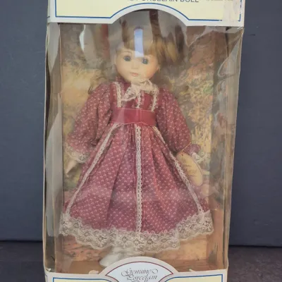 Treasured Memories Special Edition genuine porcelain doll, Margie, new in its original box, wearing a maroon patterned dress with lace trim.