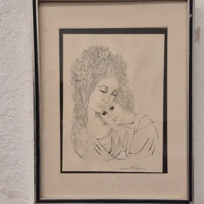 Framed black and white ink drawing depicting a mother and child, signed by Justine R Schacter, presented in a silver-toned metal frame...