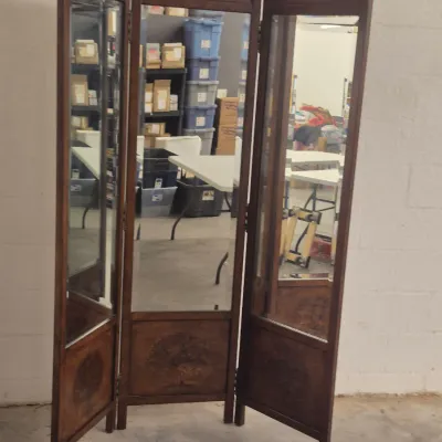 Vintage three-panel folding floor mirror with a dark wood frame, arched tops, and decorative inlaid wood details on the lower panels.