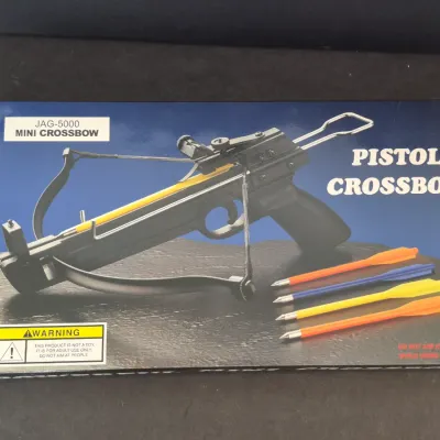 JAG-5000 Mini Crossbow in its original box, featuring a pistol-style design and four colorful bolts.
