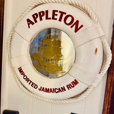Sale Photo Thumbnail #4: Vintage Appleton Imported Jamaican Rum promotional life preserver mirror, featuring a central mirror with a gold ship graphic and wrapped rope detailing.