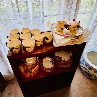 Sale Photo Thumbnail #34: Vintage Franciscan Desert Rose pattern ceramic dinnerware set, including cups, saucers, plates, and a creamer and sugar bowl set, displayed on a wooden shelf.