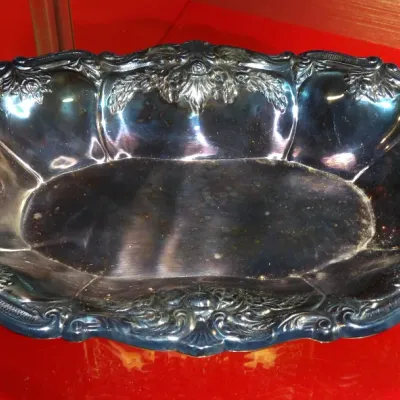 Sale Photo Thumbnail #18: Vintage silver-plated oval serving bowl featuring an ornate, scalloped rim with embossed floral and scroll details, showing some surface tarnish.