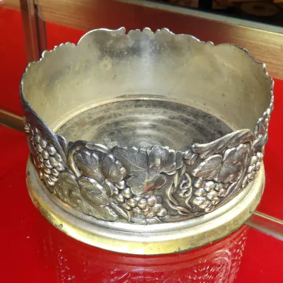 Sale Photo Thumbnail #13: Vintage silver-plated wine bottle coaster featuring an embossed grape and vine motif with a scalloped rim, showing some age-related tarnish.