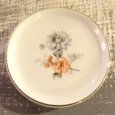 Sale Photo Thumbnail #47: Vintage Noritake porcelain butter pat or small coaster, featuring a delicate floral design with orange and grey blossoms and a gold-gilded rim.