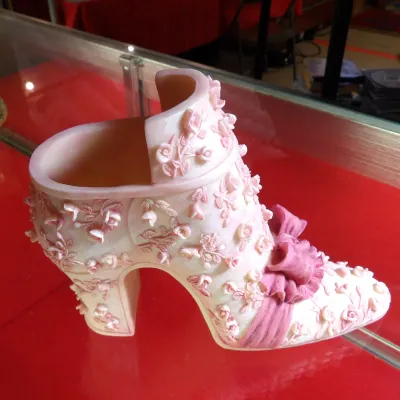 Sale Photo Thumbnail #34: Fenton Art Glass pink slag glass shoe figurine, featuring intricate raised floral rose details and a ruffled bow accent.