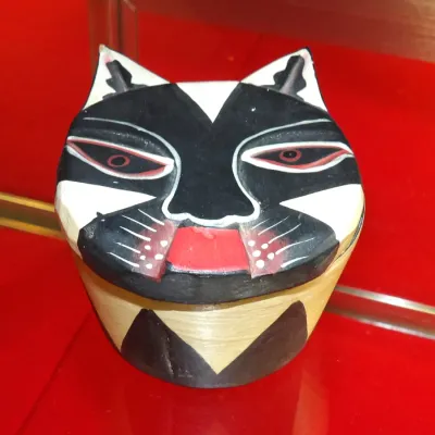 Sale Photo Thumbnail #22: Hand-carved and painted wooden cat trinket box, featuring a stylized black, white, and red feline face on the lid.