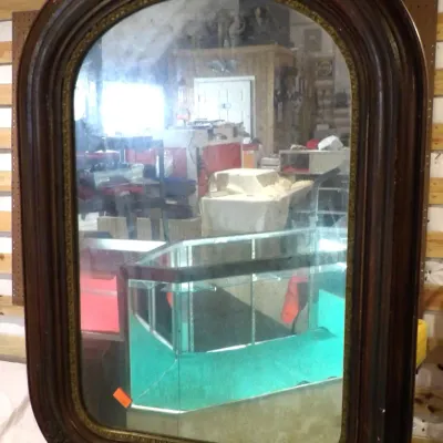Sale Photo Thumbnail #40: Antique Victorian-era wall mirror featuring an arched dark wood frame with carved details and a gilded inner border.