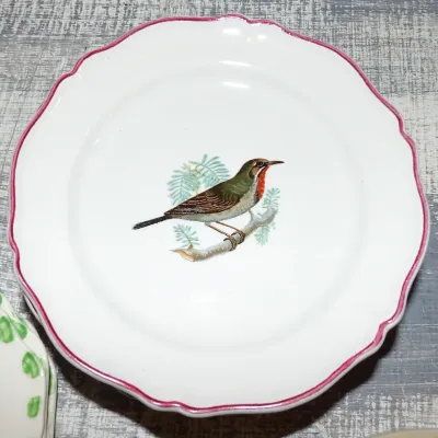 Sale Photo Thumbnail #46: Vintage Gien France earthenware plate featuring a hand-painted bird perched on a branch, finished with a scalloped pink rim.
