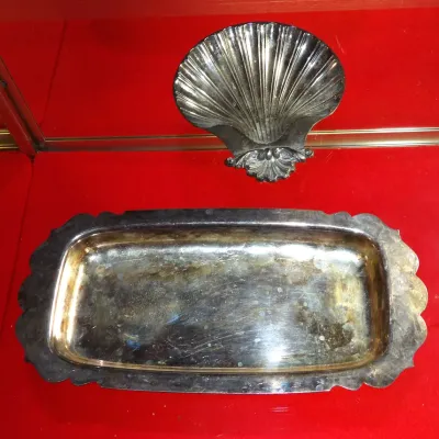 Sale Photo Thumbnail #15: Vintage silver-plated serving pieces, including a scalloped rectangular tray and a shell-shaped dish, showing some surface tarnish.