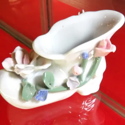 Sale Photo Thumbnail #29: Vintage porcelain miniature shoe figurine, likely of German or Japanese origin, featuring delicate applied ceramic flowers and green vines on a white glazed body.