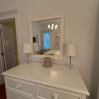 White wooden dresser paired with a matching wall mirror, accompanied by a set of modern table lamps.