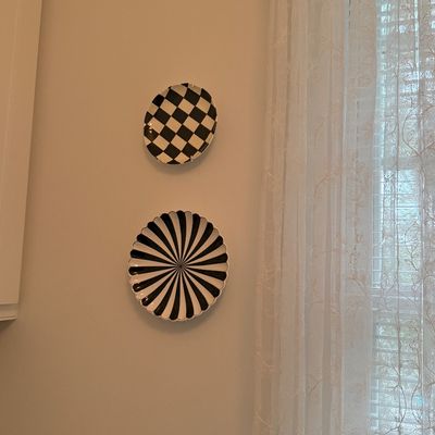 Pair of black and white decorative wall plates featuring checkerboard and starburst optical pattern designs.