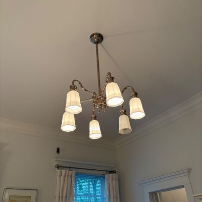 Traditional brass six-light chandelier featuring curved arms and frosted ribbed glass shades, mounted on a plain white ceiling.