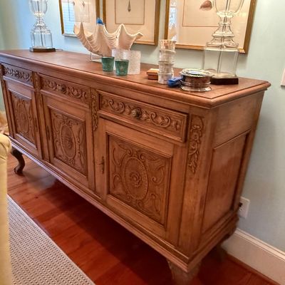 French Provincial style carved wood sideboard featuring ornate door panels, three top drawers, and cabriole front feet.